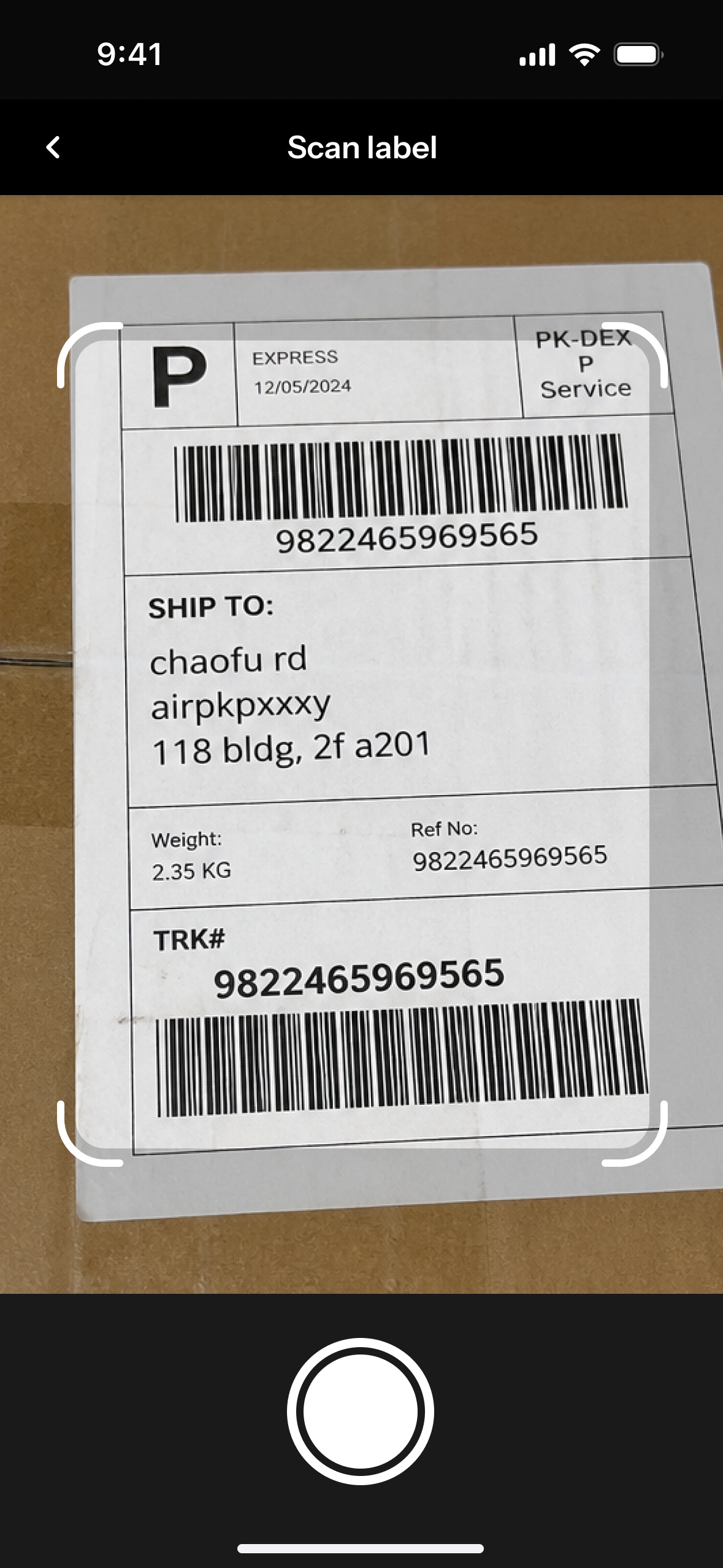 The scan-label screen in the warehouse tool: a courier label held in the capture frame, its shipping block reading Chaofu Road, AIRPKPXXXY, 118 building, 2F A201, beside the service name, the date, a 2.35 kg weight and the tracking number repeated as TRK and reference number.